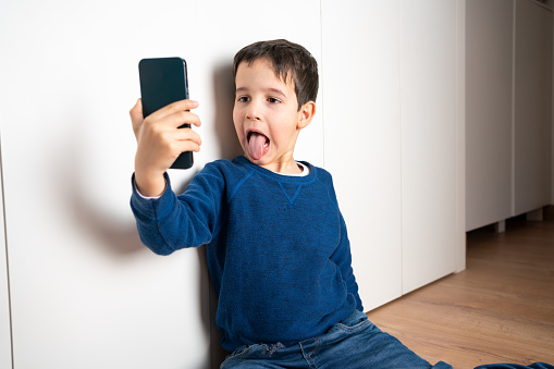 Showing his silly side.Shot of a child sticking his tongue out while taking a selfie at home.