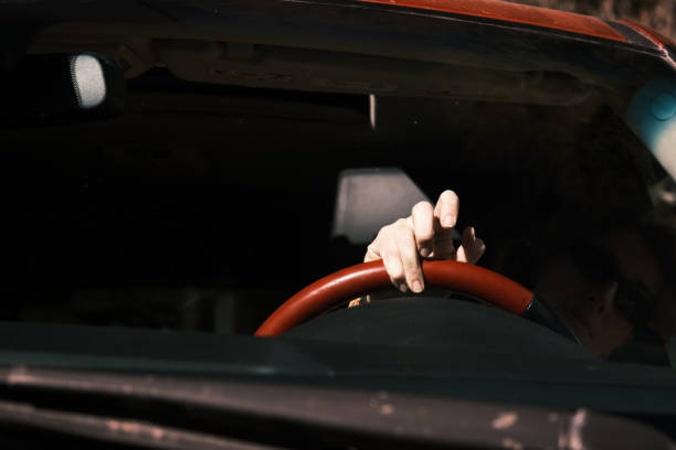Female hand is nervously drumming her fingers on steering wheel