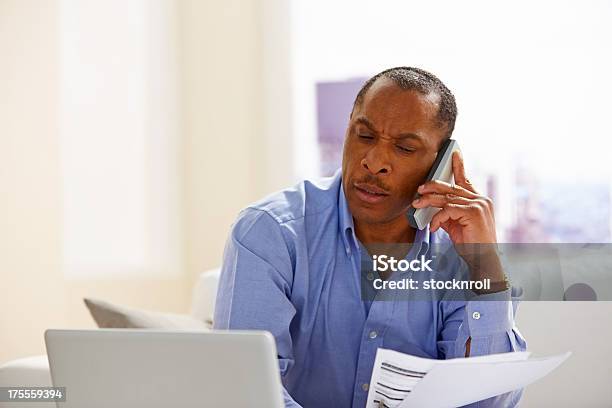 African Man Calculating His Monthly Expenses Stock Photo - Download Image Now - African-American Ethnicity, Cordless Phone, 40-44 Years