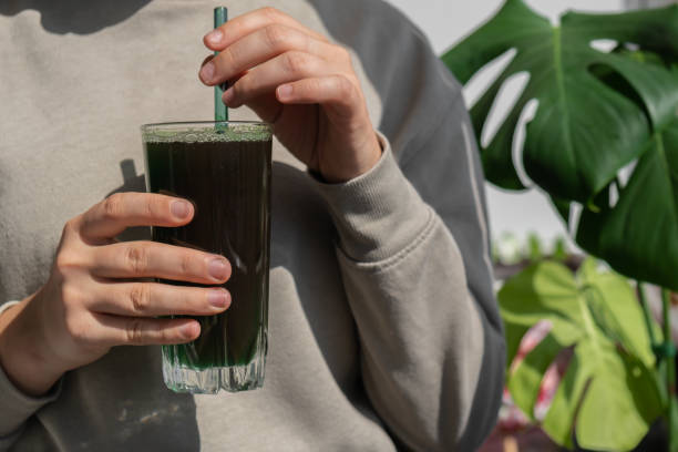 kobiece ręce trzymające organiczny napój detoksykacyjny spirulina z niebiesko-zielonych alg w szklanym proszku spożywczym. zdrowy koktajl białkowy koktajl z chlorelli. witaminy i minerały w diecie. bogaty w prebiotyki i antyoksydanty suplement diety  - chlorofil zdjęcia i obrazy z banku zdjęć