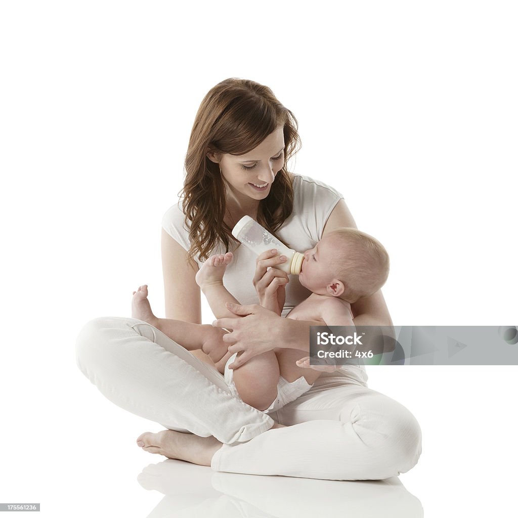 Smiling mom feeding her baby with milk Smiling mom feeding her baby with milkhttp://www.twodozendesign.info/i/1.png Baby - Human Age Stock Photo