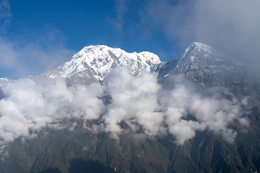 A panoramic view of a majestic mountain range with fast-moving clouds skirting the sky above