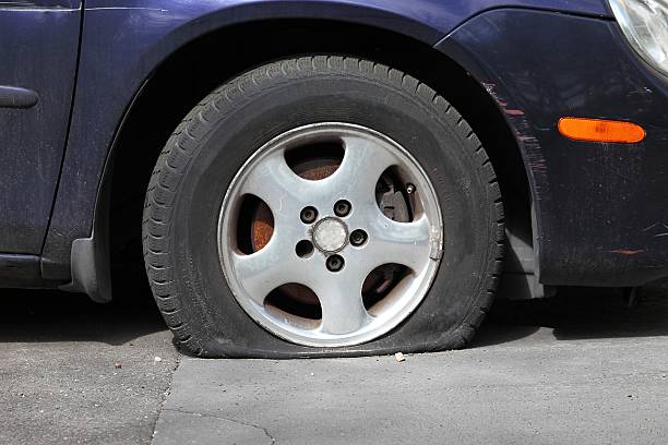 istock Very flat tire on blue sedan parked on concrete driveway 175563736