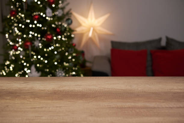 istock Table top with blurred living room background with Christmas tree and decorations. 1755639317
