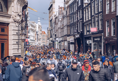 Crowd of people walking down the street in center of Amsterdam on King's Day celebration. AMSTERDAM,NETHERLANDS-28 APRIL,2019