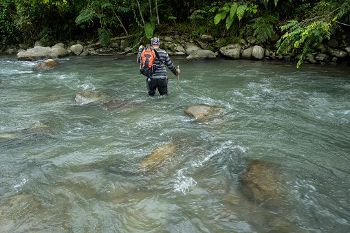 Men crossing a deep river during a forest walk