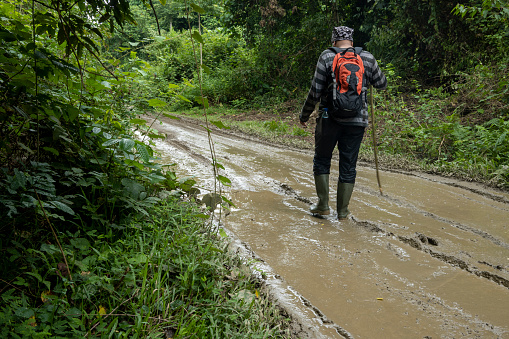Man walks on a muddy road wearing boots
