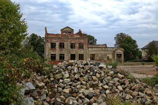 Ruins of an old residential building with heap of stones.
