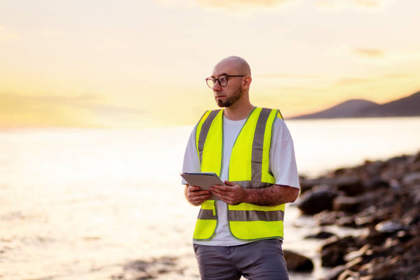 Inspection environmentalist. Volunteer man wearing vest using pad for analyzing water. Copy space. Concept of air and ocean pollution