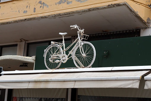 White decorative bike on top a storefront roof awning
