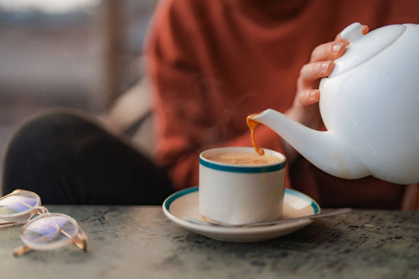 femme versant du masala chai dans la tasse - patan photos et images de collection