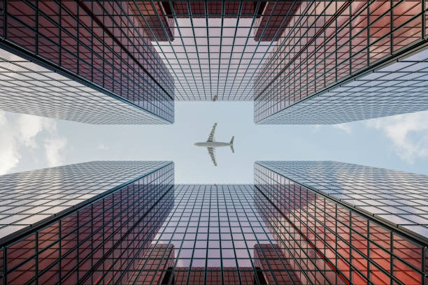 istock Skyscraper with Glass Curtain Wall, Reflecting Sky and Clouds, as an Airplane Passes By 1755685206