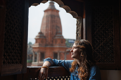 Woman sitting on the  balcony  in oriental style overlooking Bhaktapur Durbar Square