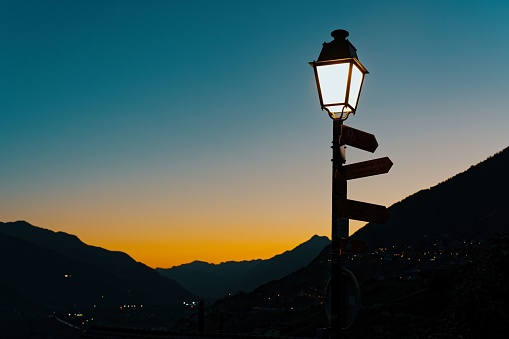 A picturesque scene of a street light against a backdrop of a mountain range during the sunset