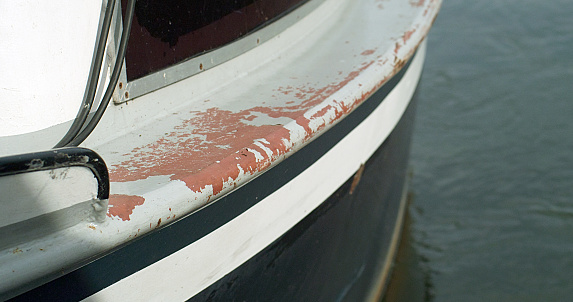 DIY old rusted boat restoration project. Scraping off the old layer of paint and repainting with new coat.