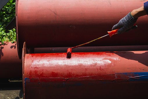 Rust-proof painted steel pipes in the factory. Red iron pipe. Rust-proof paint, water pipes