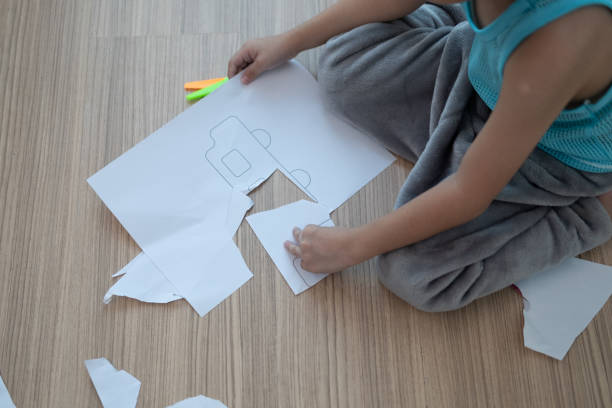 istock Asian boy using scissors to cut paper along lines Learning outside the classroom 1755730790