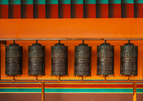Prayer wheels on orange background  in Tibetan monastery