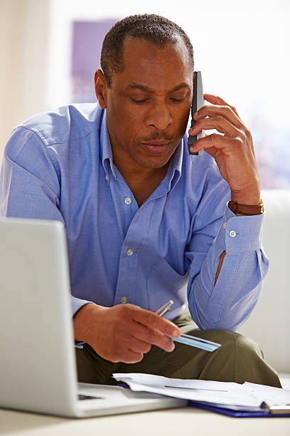 istock Thoughtful middle aged man with credit card talking on phone 175574850
