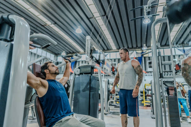 istock Mature man exercising with a personal trainer at the gym 1755750272