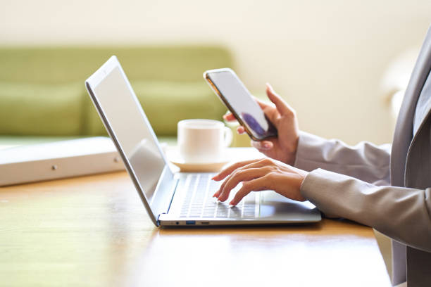istock Asian woman operating a computer and smartphone at a cafe 1755760011