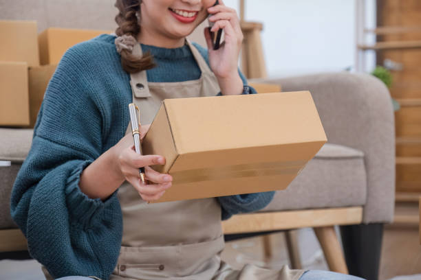 istock Small start-up business owners using phones at work, salespeople, checking production orders. Pack products to ship to customers, sell ecommerce shipping ideas. 1755761830