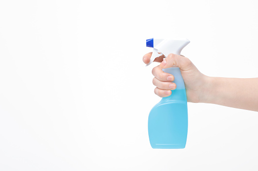 Hand with light blue spray bottle - against a white background