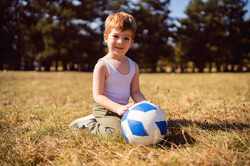 Portrait of a boy playing with soccer ball outside.