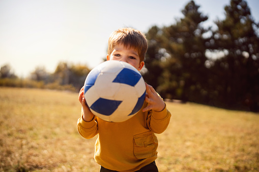 Portrait of a boy playing with soccer ball outside.