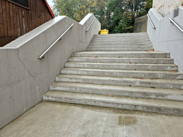 istock a staircase with concrete sides at a public building. the safe staircase has two handrails, one with a reduced height for children under 12 at the entrance to the school, brick, black, red. forgery 1755771019