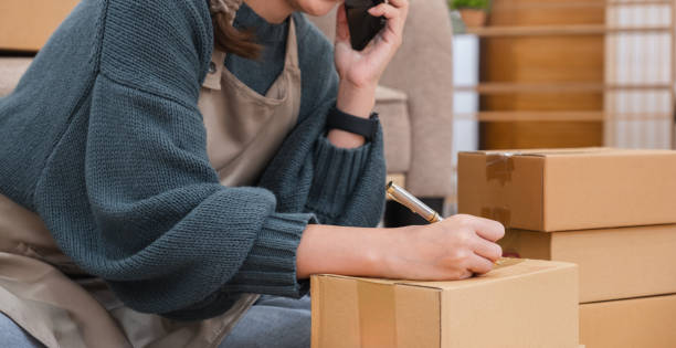 close up, Startup small business entrepreneur SME, asian woman packing cloth in box. Portrait young Asian small business owner home office, online sell marketing delivery close up, Startup small business entrepreneur SME, asian woman packing cloth in box. Portrait young Asian small business owner home office, online sell marketing delivery. newspaper seller stock pictures, royalty-free photos & images