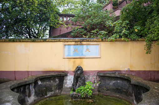 A spring pool in a Chinese-style courtyard. Two Chinese characters on the wall read \