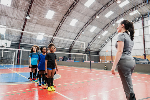Children listening to teacher at a sports court
