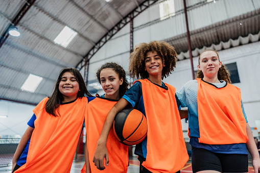 Portrait of children holding a basketball ball at a sports court