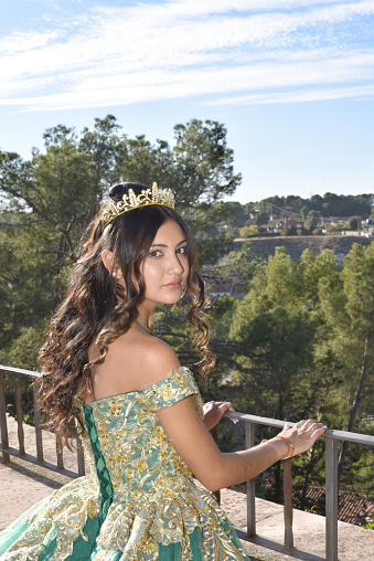 Beautiful young girl in a long green dress with a crown on her head