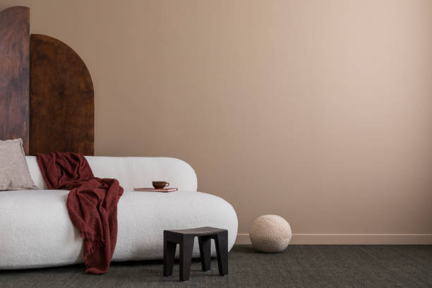 Minimalist composition of cozy living room interior with copy space, boucle sofa round pillow, brown wall and personal accessories. Home decor. Template.