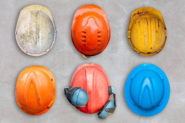 istock Six colorful old and worn construction helmets hanging on a concrete wall 1755817571