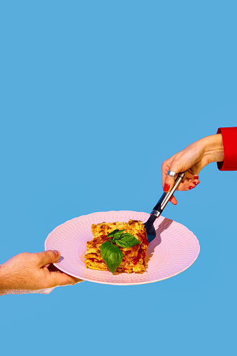 Female hand serving delicious Italian food, putting lasagna on plate over green and blue background. Bolognese sauce. Concept of Italian food, cuisine, taste, cooking, menu. Pop art. Poster, ad
