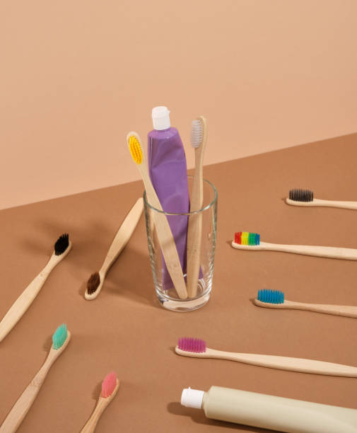 istock Ecological toothbrushes with colorful bristles scattered on the table. Two toothbrushes and toothpaste in a glass. 1755829885