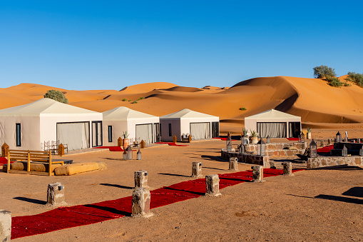 Luxury camp in Western Sahara Desert, Morocco. Tents are at the edge of the Sahara desert with dunes visible in the background.