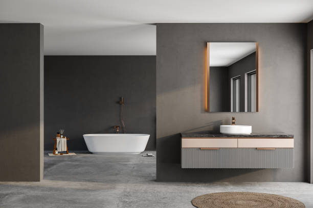 istock Modern minimalist bathroom interior, modern bathroom cabinet, white sink, wooden vanity, interior plants, bathroom accessories, bathtub, black walls, concrete floor. 1755846336