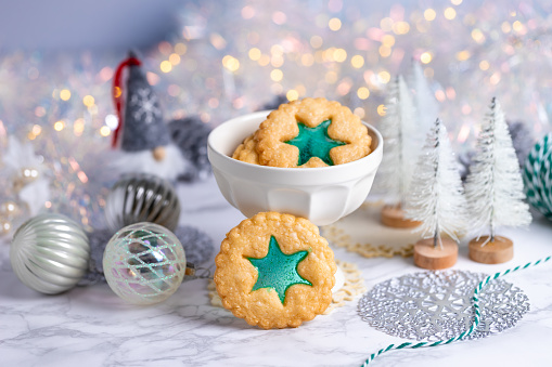 Christmas homemade stained glass cookies on marble background with bokeh lights, selective focus