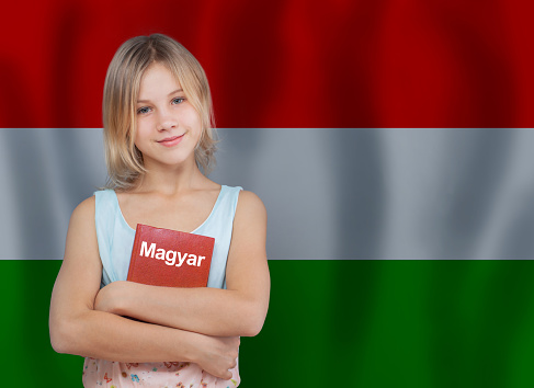 Attractive preteen girl and book with inscription Hungarian in Hungarian language on flag of Hungary background