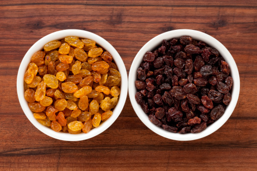 Two bowls containing the light and dark raisins varieties