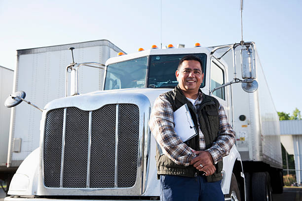 Hispanic truck driver with clipboard Hispanic truck driver (40s) standing in front of semi-truck with clipboard. haulage stock pictures, royalty-free photos & images