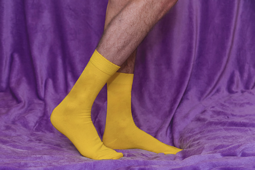 Legs of a man in yellow socks on a purple background.
