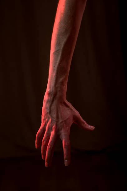 istock hand on a black background with a red light in the studio 1755860990