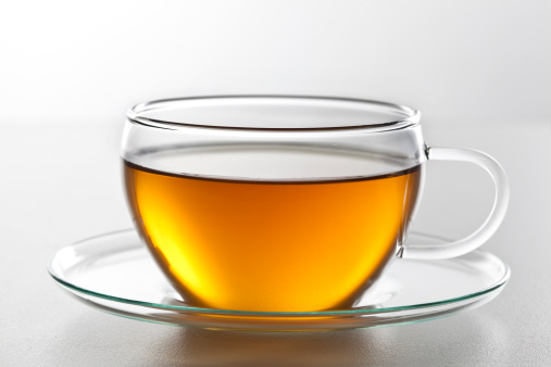 Cup of tea with pill inside on a wooden table.