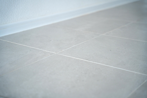 Close-up of tiled floor and a baseboard at the wall