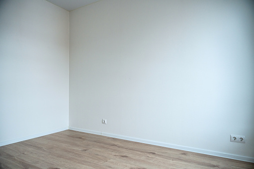 An empty room interior, white walls and wooden laminate on the floor